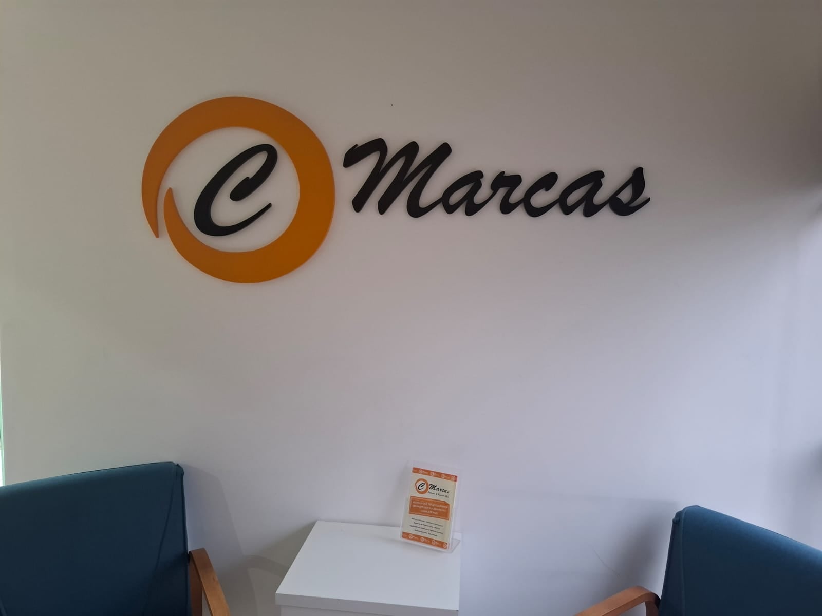 Logotipo CMarcas em parede branca do escritório